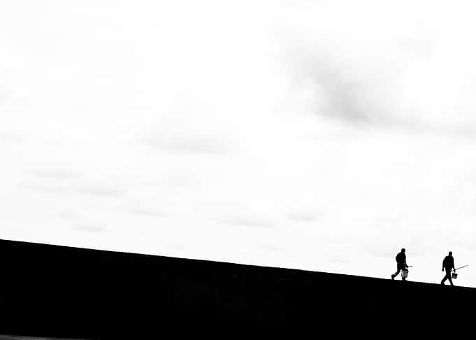 Two figures walking on a dark slope
