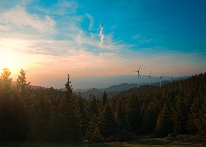 Wind Turbines in a Mountainous Forest at Sunset