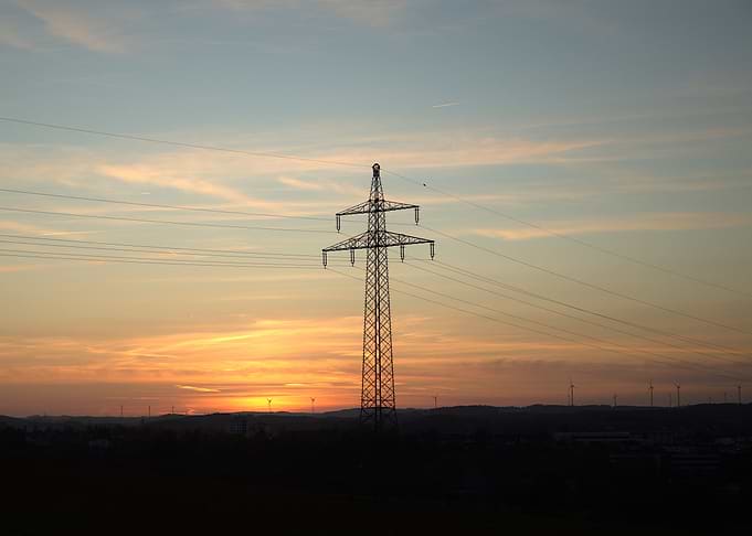 Sunset over rolling hills with power lines