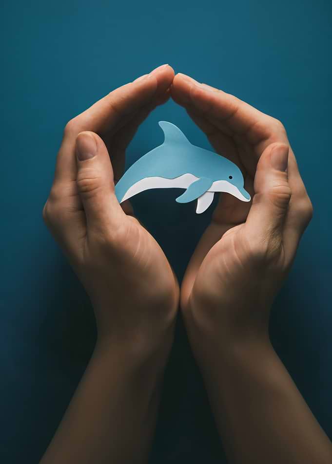 Hands protecting a paper dolphin