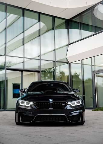 Black BMW M4 in front of modern building