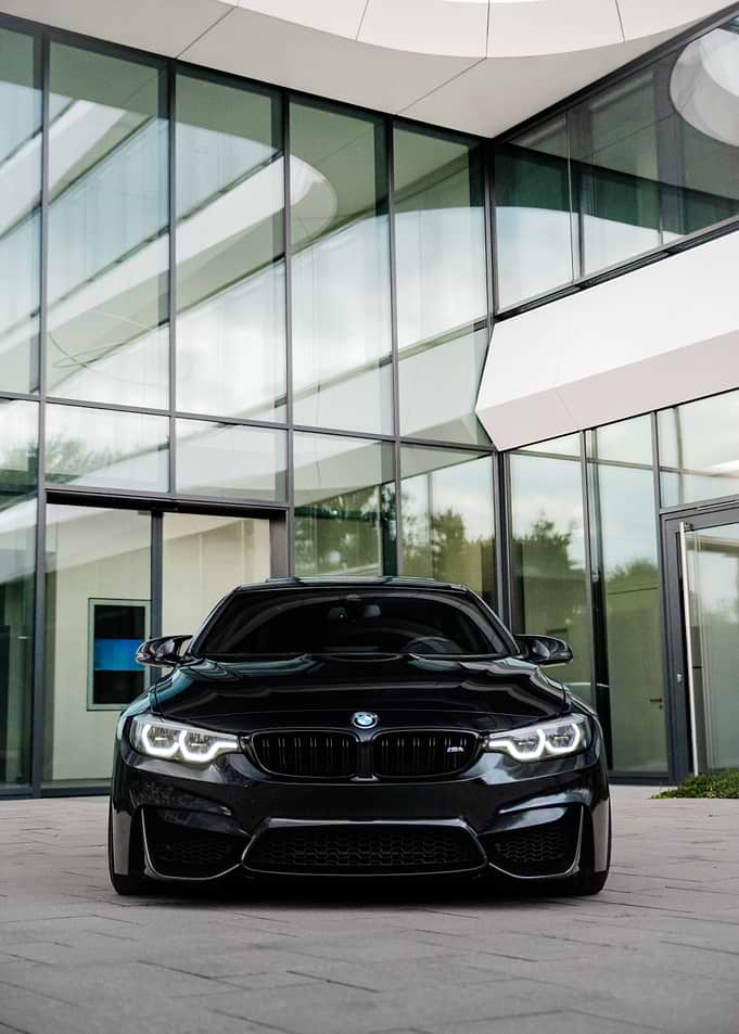 Black BMW M4 in front of modern building