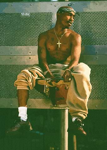 Tupac Shakur sitting outdoors
