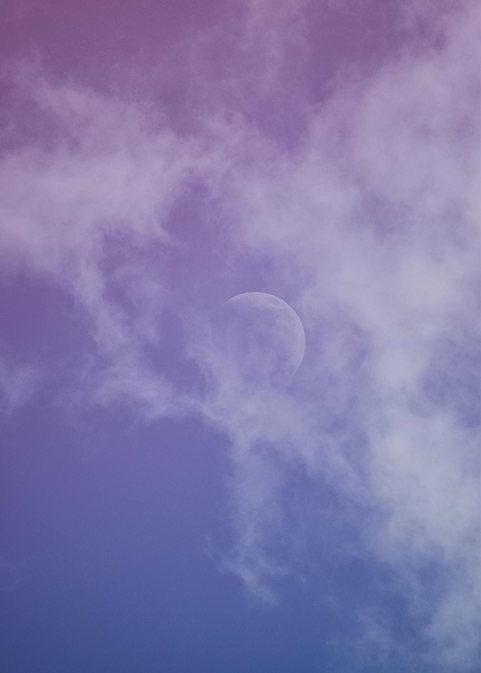 Moon peeking through purple clouds