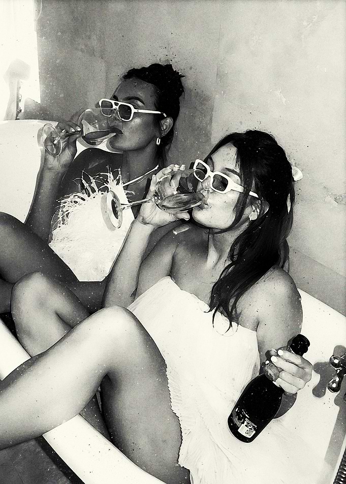 Two women drinking champagne in a bathtub