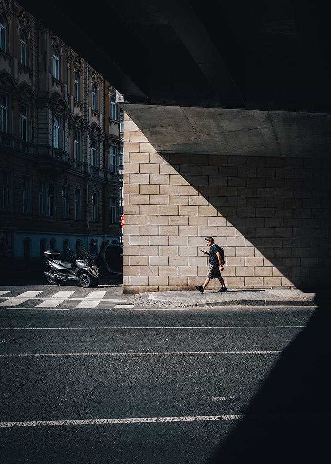 Man walking under bridge in city