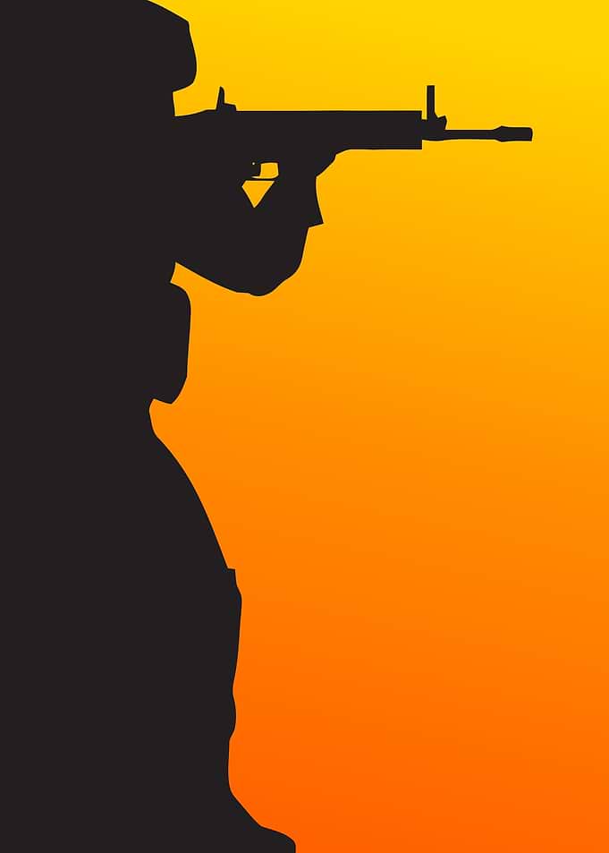 Soldier aiming rifle at sunset