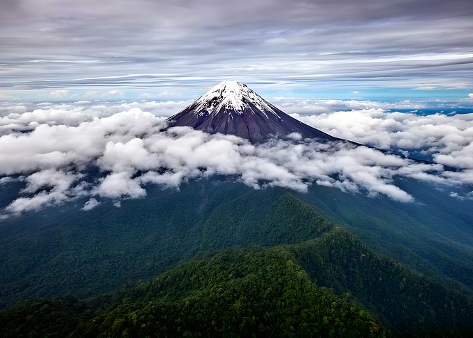 Snow-capped volcano above clouds
