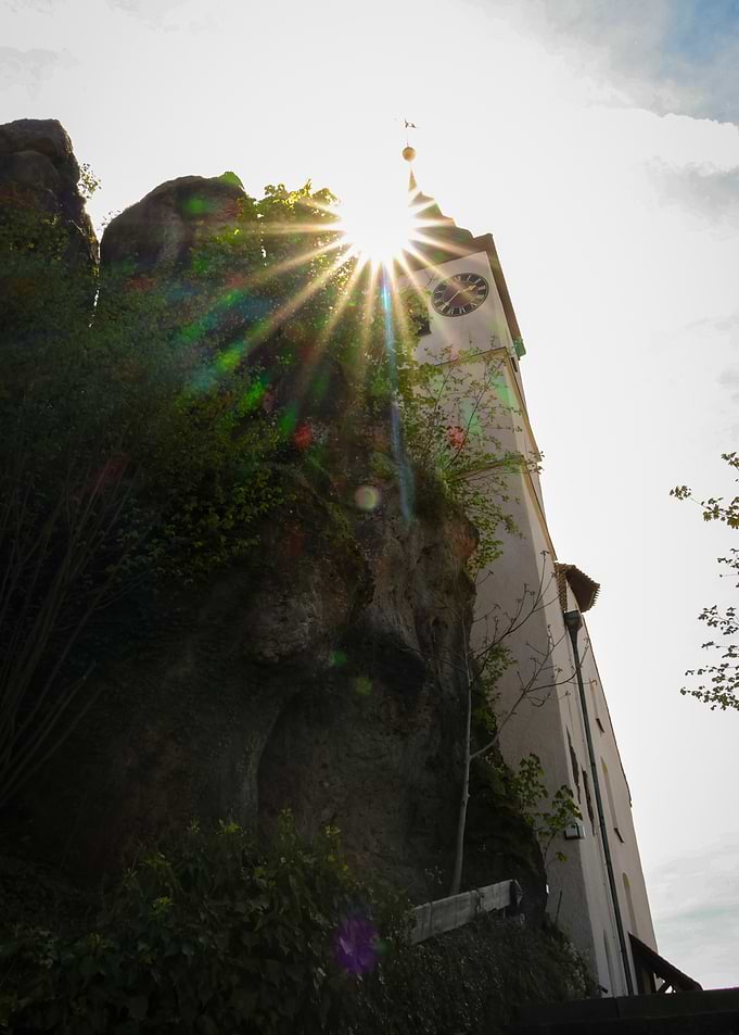 Sunburst over a Church Tower and Rocks