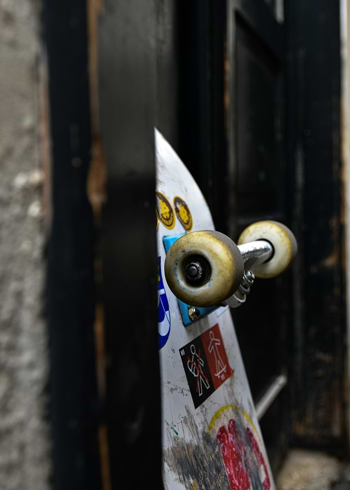 Skateboard with stickers leaning against a door