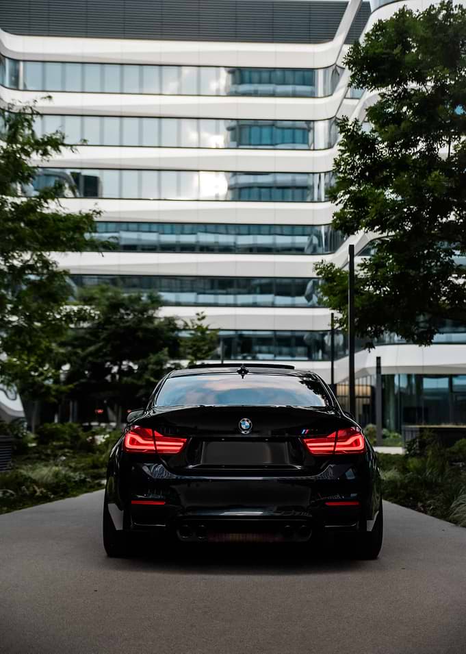 Black BMW M4 parked in front of modern building