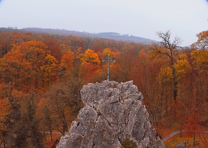 Cross on a rocky outcrop in autumn forest