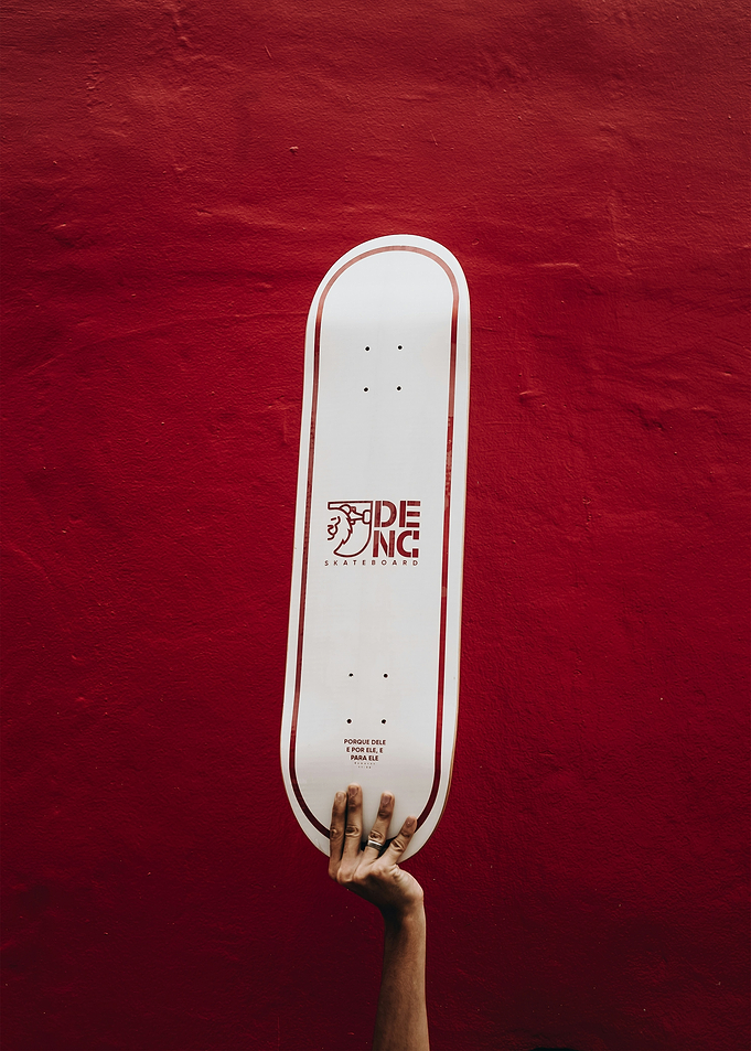 Skateboard held against red wall