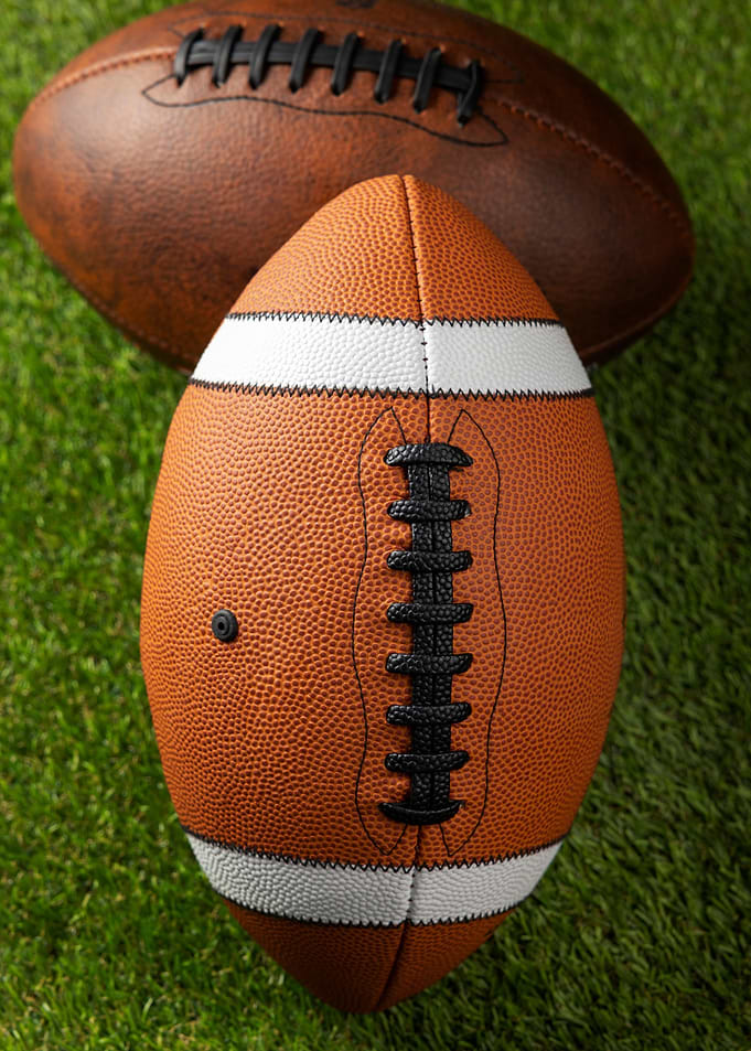 Two American Footballs on Grass