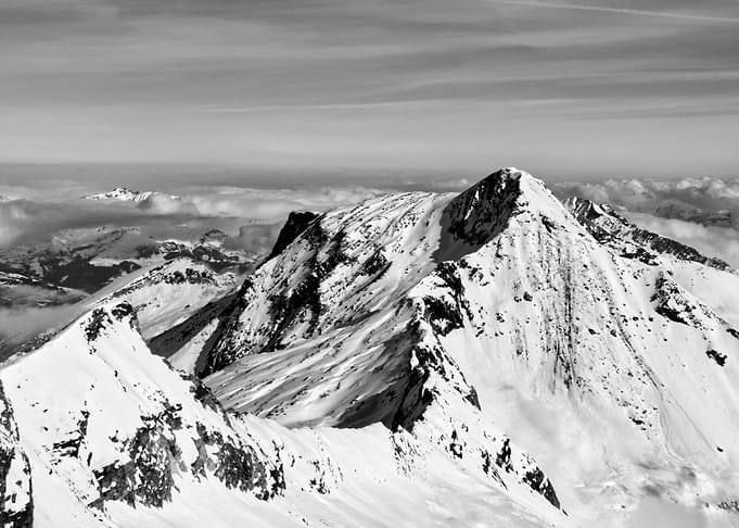 Snow-covered mountain peaks under a cloudy sky