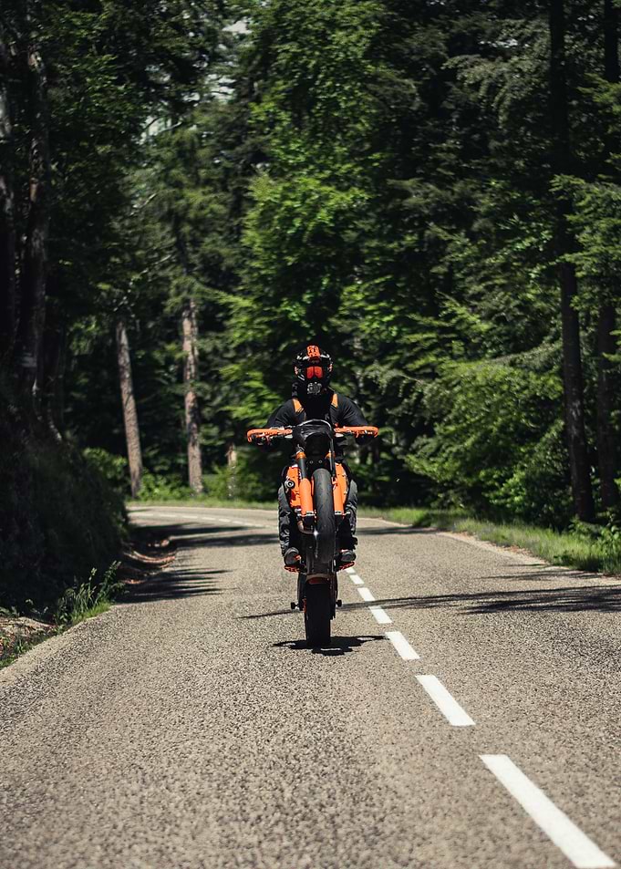Motorcyclist doing a wheelie on a forest road