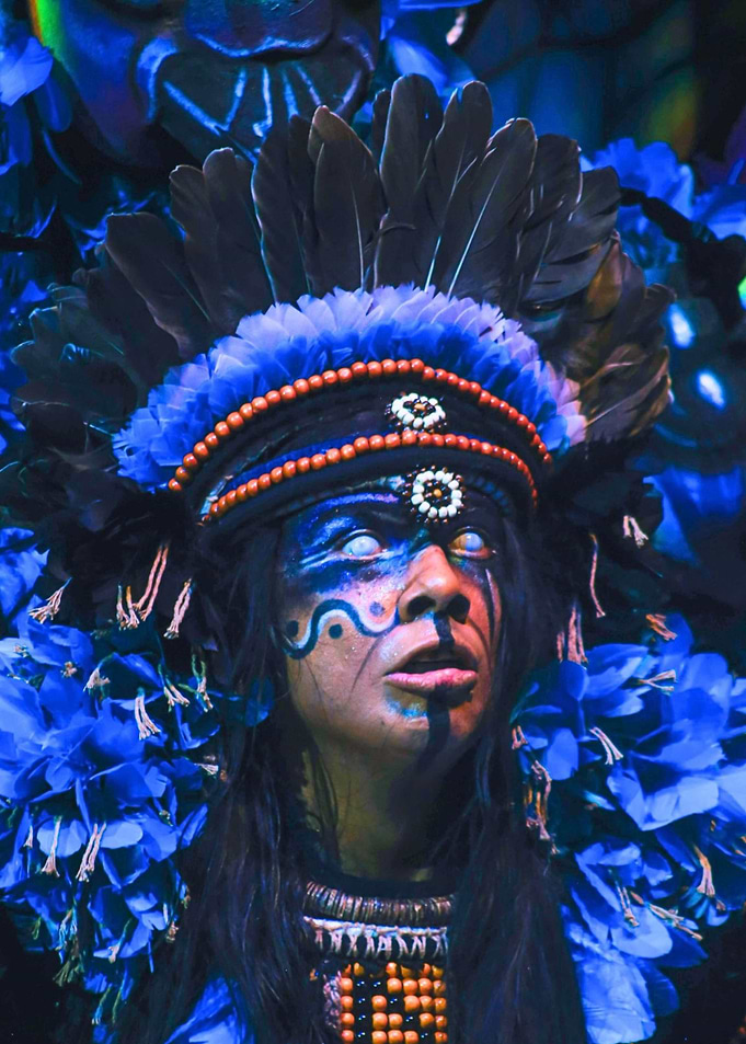 Person in elaborate blue headdress and face paint