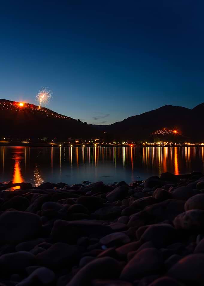 Fireworks over a river at dusk