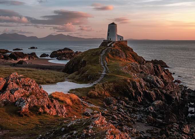 Lighthouse on a rocky outcrop at sunset