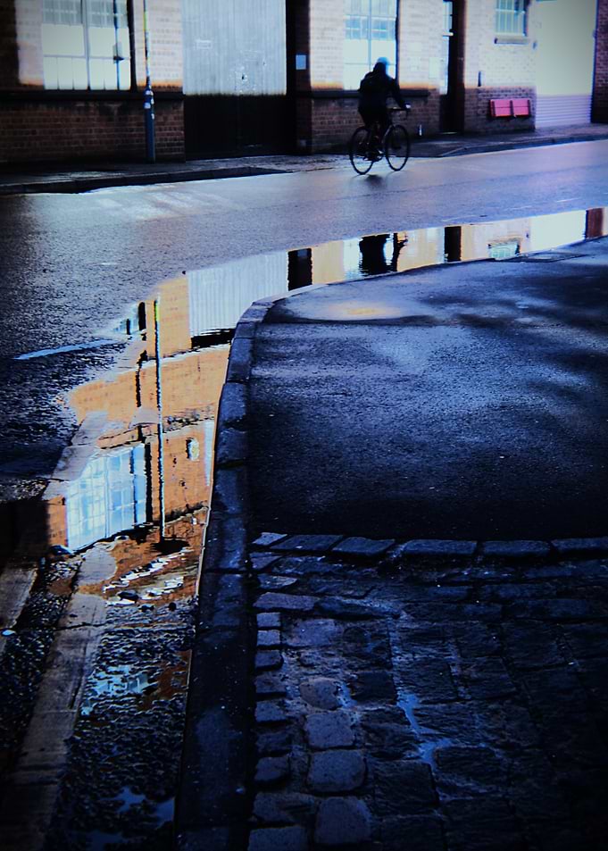 Cyclist reflected in a puddle