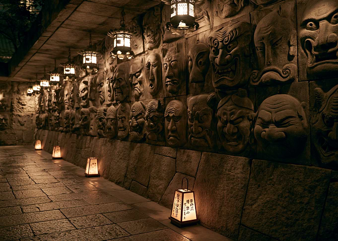 Stone Wall with Carved Faces and Lanterns