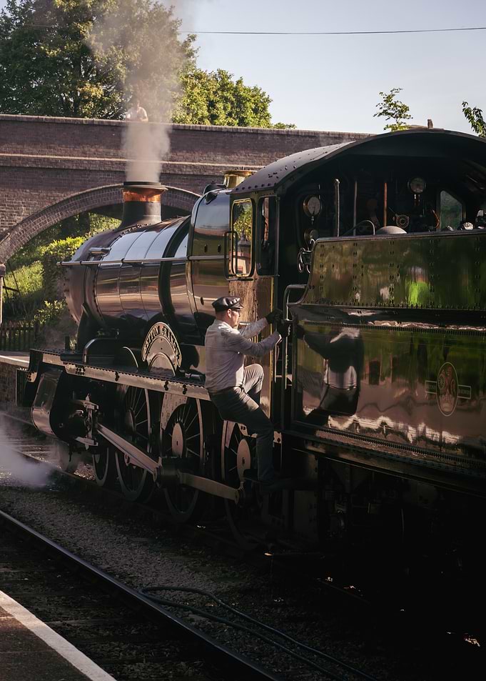 Train driver climbing onto steam engine