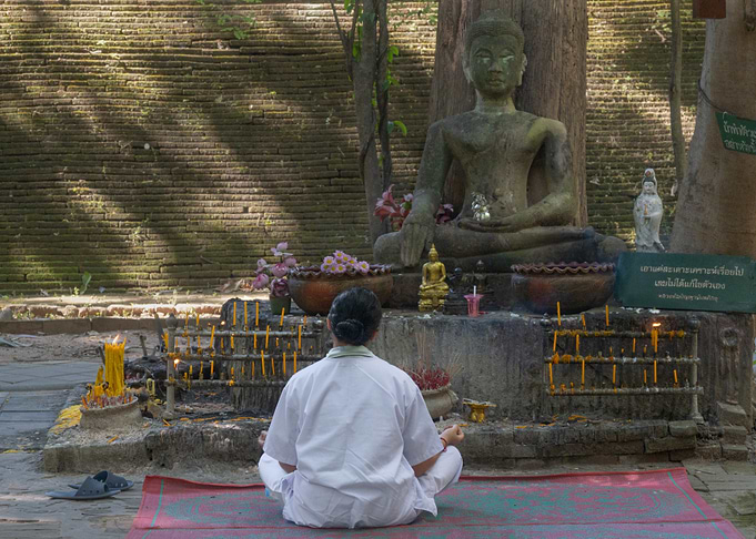 Woman Meditating Before Buddha Statue