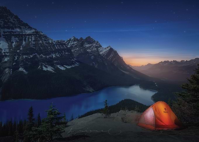 Camping tent by a mountain lake at night