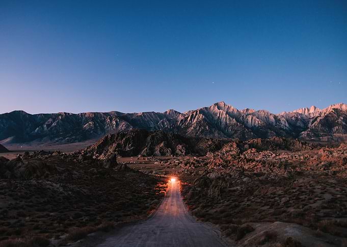 Desert Road Leading to Mountains at Dusk
