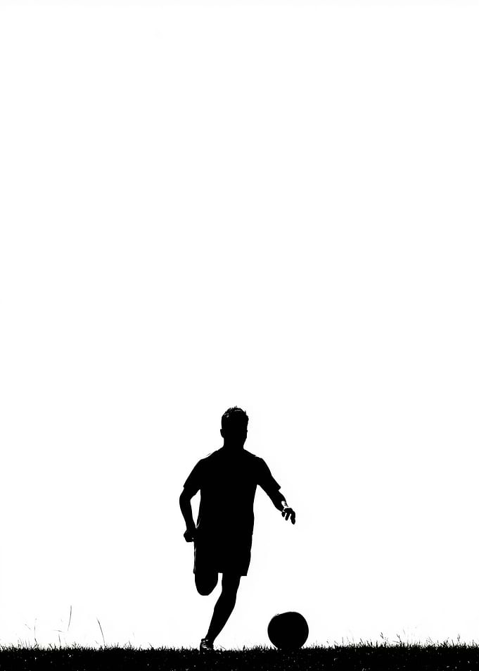 Silhouette of a soccer player kicking a ball