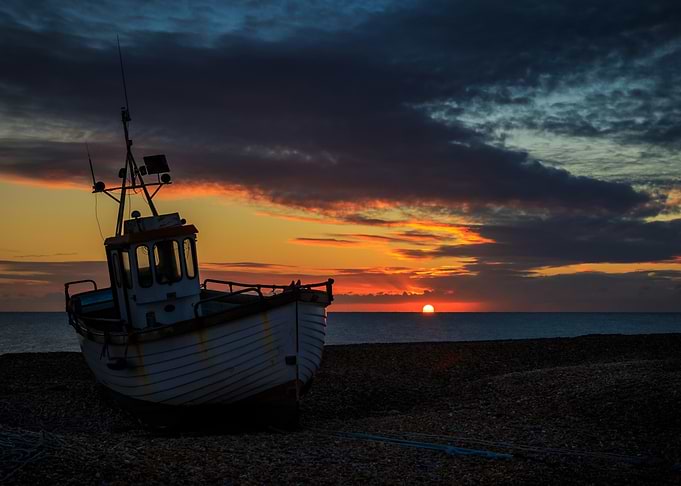 Fishing boat at sunset on a pebble beach