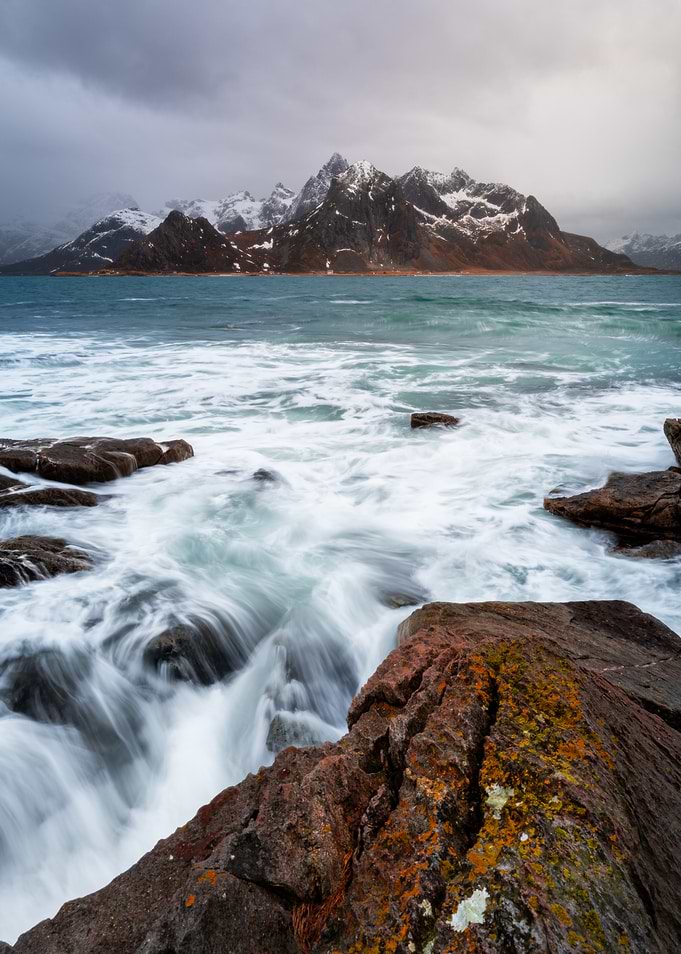 Waves crashing on rocky shore with mountains