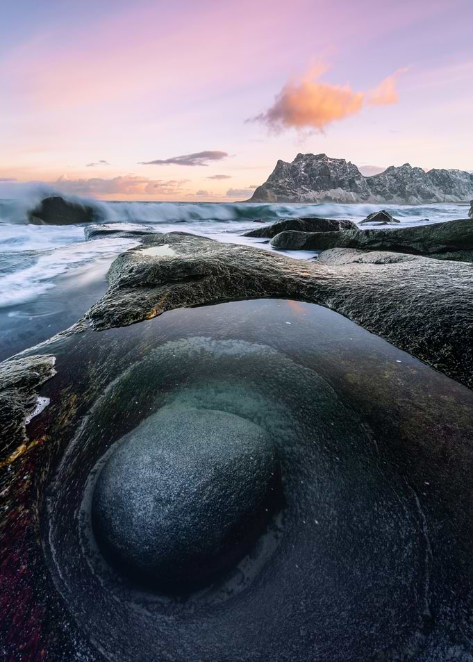 Ocean waves crashing on rocky shore at sunset
