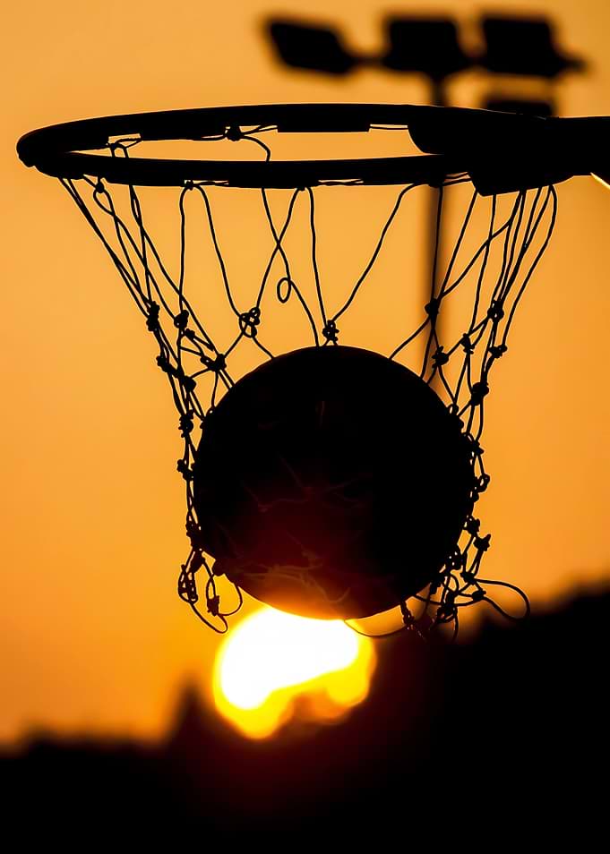 Basketball going through hoop at sunset