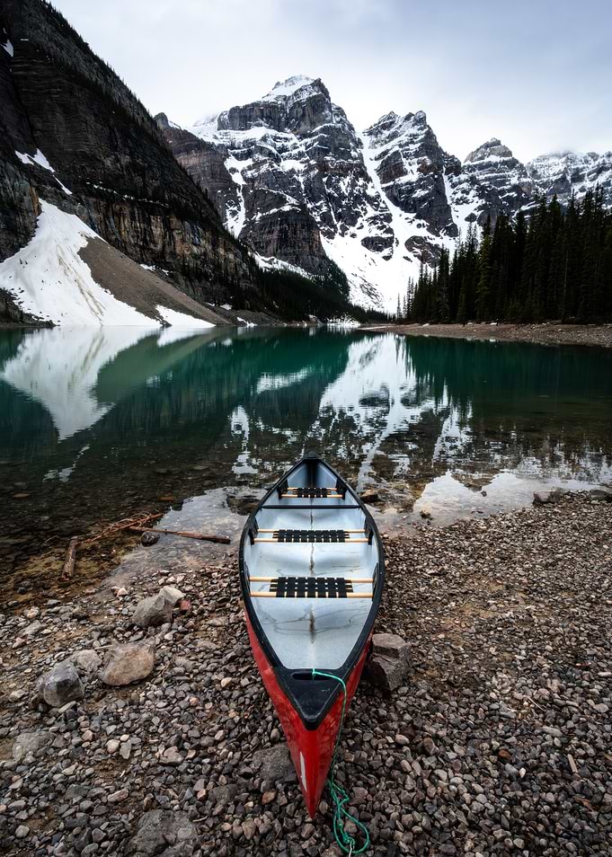 Canoe on Rocky Shoreline with Mountains