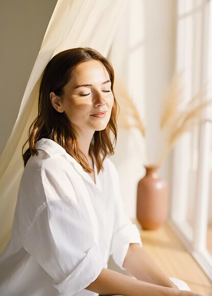 Woman enjoying sunlight by the window