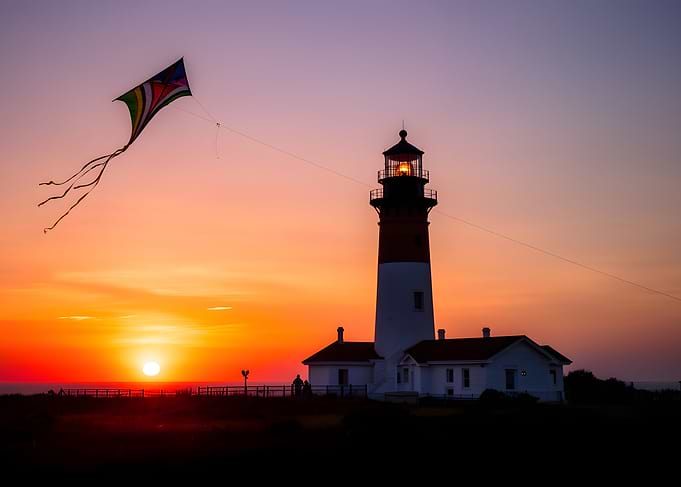 Kite flying at sunset near lighthouse