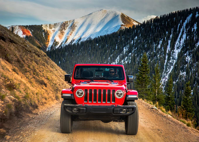 Red Jeep driving on mountain road