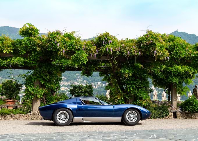 Blue Lamborghini Miura parked under wisteria