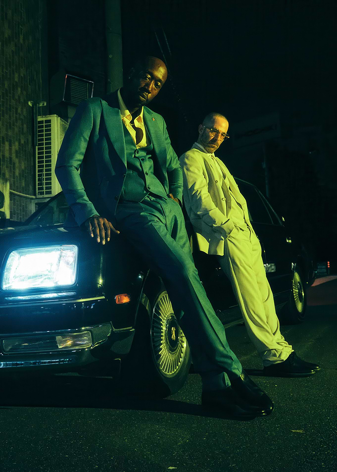 Two men in suits by a car at night