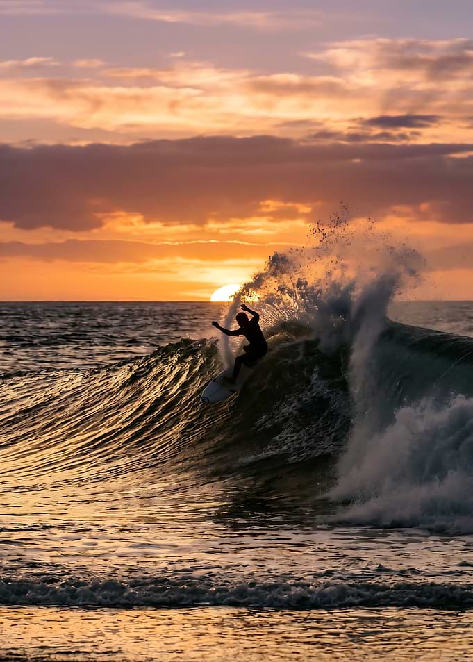 Surfer riding a wave at sunset