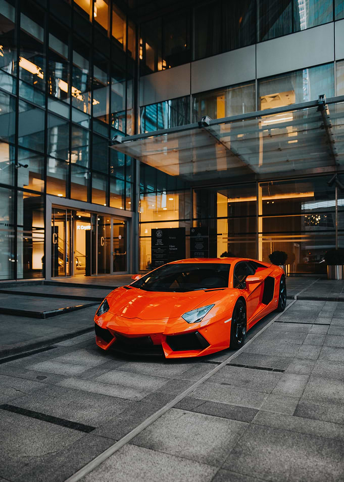Orange Lamborghini Aventador parked outside modern building