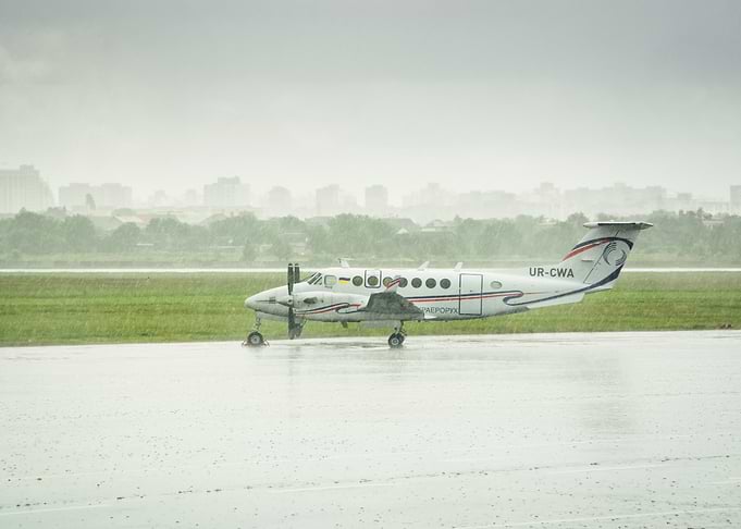 Beechcraft King Air on airport apron amid heavy rain.