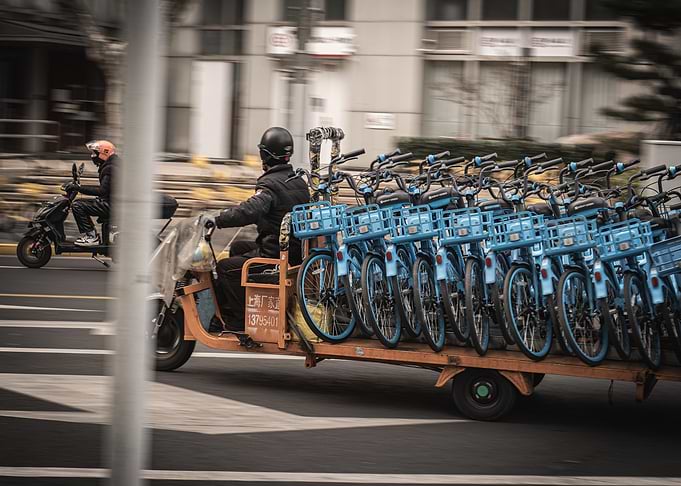 Worker Transporting Blue Rental Bicycles