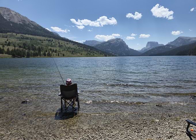 Person fishing near sweetwater valley and mountains