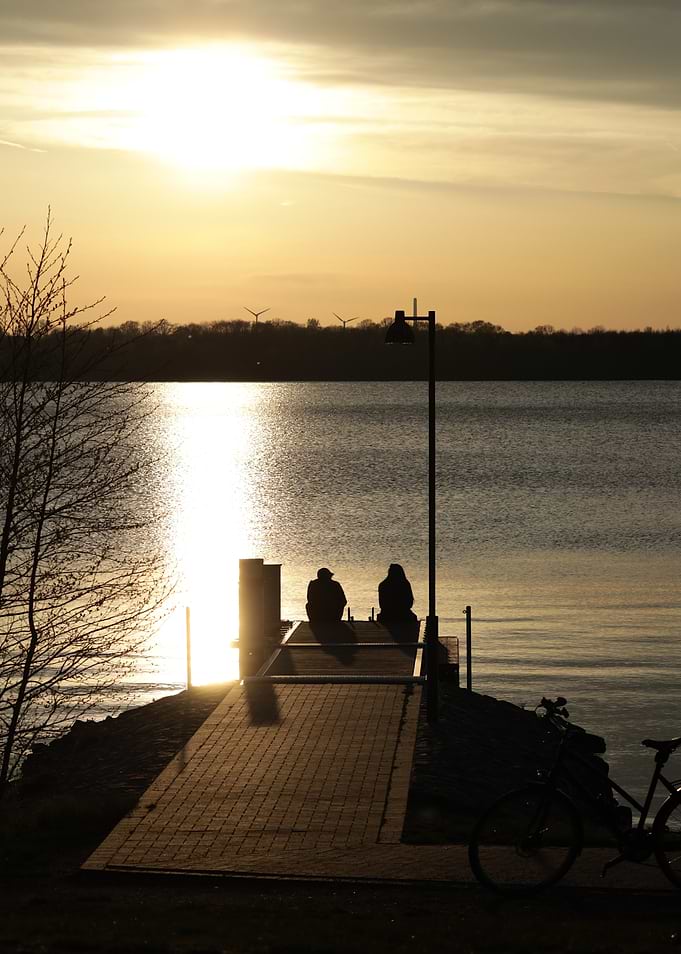 Couple sitting on pier at sunset