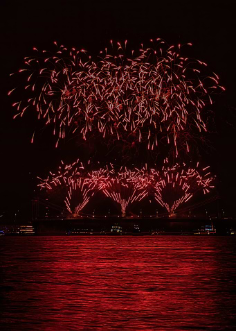 Red Fireworks Over City Bridge
