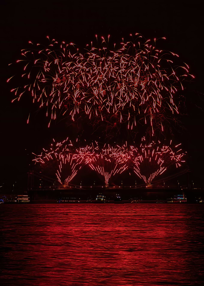 Red Fireworks Over City Bridge