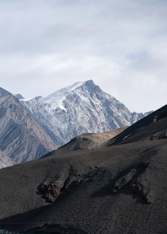 Snow-Capped Mountain Peak Over Dark Hills