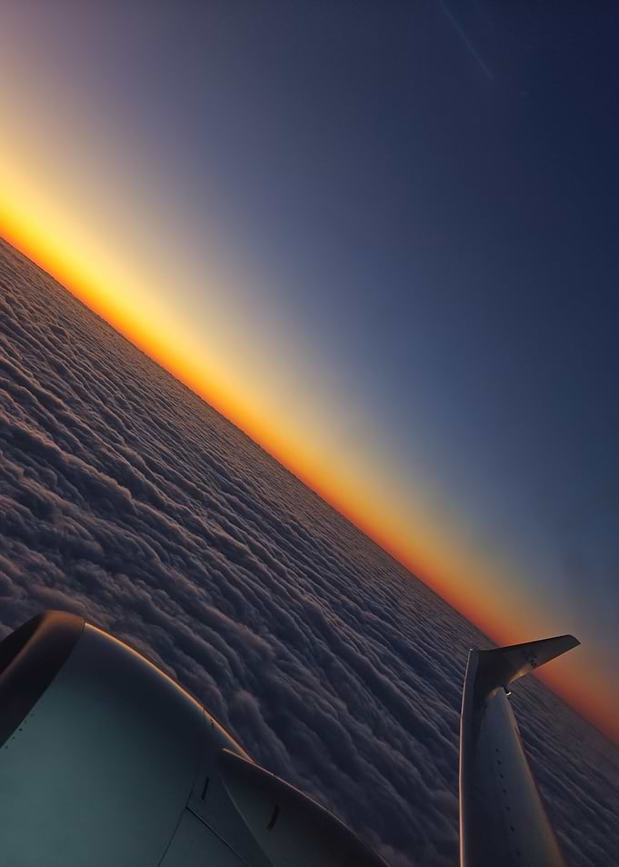 Airplane Wing Above Clouds at Sunset